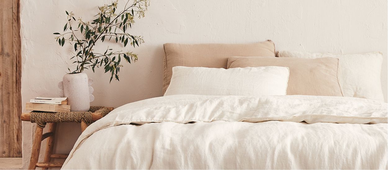 Chambre avec parure de lit en chanvre écru respirant, oreiller en latex naturel et détails naturels, illustrant l'importance du linge respirant pour l'hydratation et le sommeil en période chaude