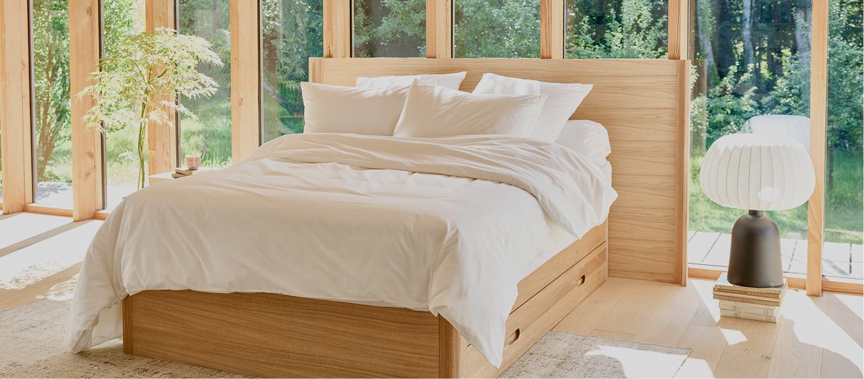Chambre avec linge de lit blanc naturel et lit bois montrant literie respirante adaptée à la canicule