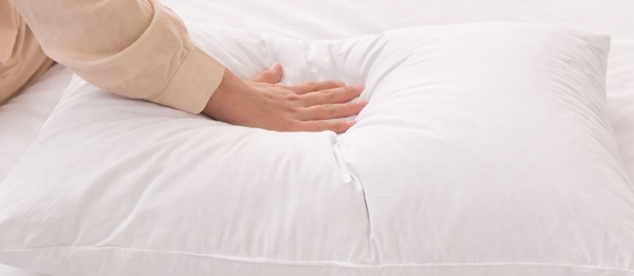 Main posée sur oreiller blanc Kipli montrant texture douce et confort supérieur du latex naturel