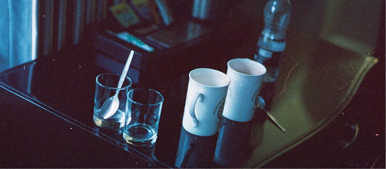 Petite bouteille d'eau fraîche et verres posés près du lit la nuit, illustrant l'importance d'avoir de l'eau à proximité en cas de réveil assoiffé pendant les fortes chaleurs