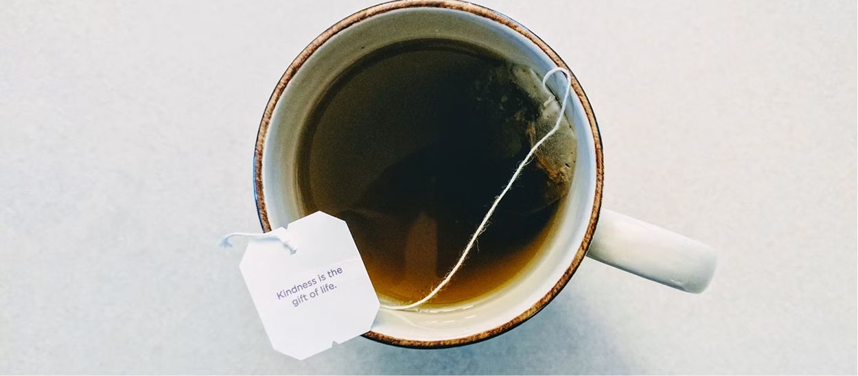 Tasse de thé chaud avec sachet de tisane reposant sur une surface blanche, illustrant les remèdes naturels et les rituels apaisants pour favoriser le sommeil et adapter son horloge biologique après un décalage horaire