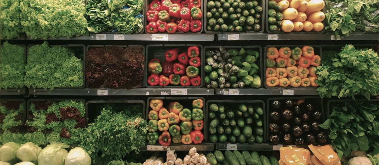 Étalage de marché vue de dessus avec fruits et légumes frais colorés, ilustrant l'importance de la nutrition et des protéines pour la production de mélatonine et un meilleur sommeil
