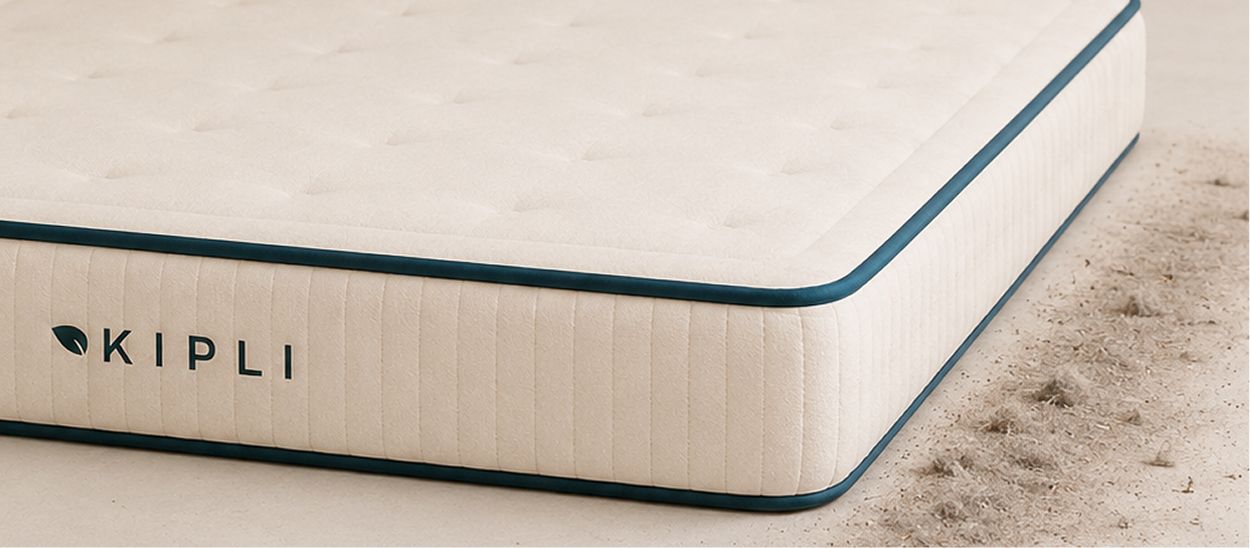 Vue rapprochée d'un matelas Kipli posé au sol, montrant de la poussière accumulée juste à côté.