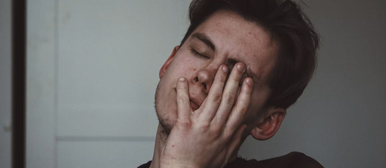 Personne stressée et fatiguée avec la main sur le visage, illustrant l'impact du stress et de l'anxiété sur le sommeil et le cercle vicieux insomnie-stress qui en découle