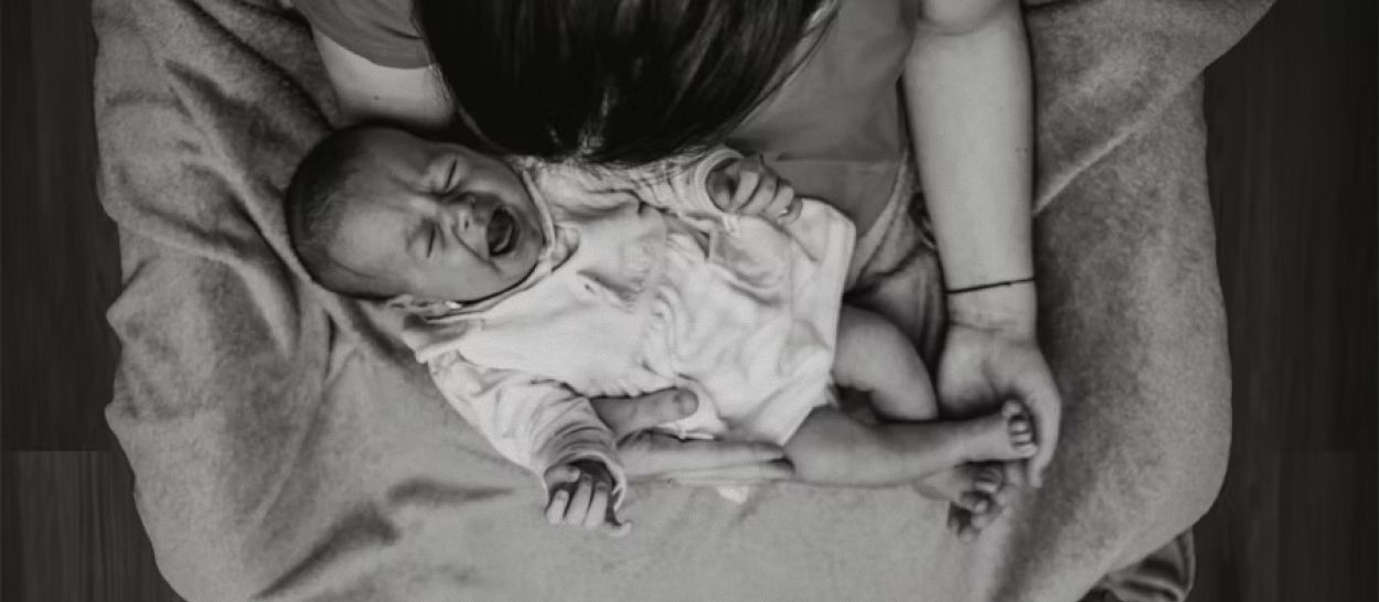 Nourrisson dans les bras d'un parent qui l'apaise, illustrant l'usage du bruit blanc pour aider bébé à se calmer et à trouver le sommeil