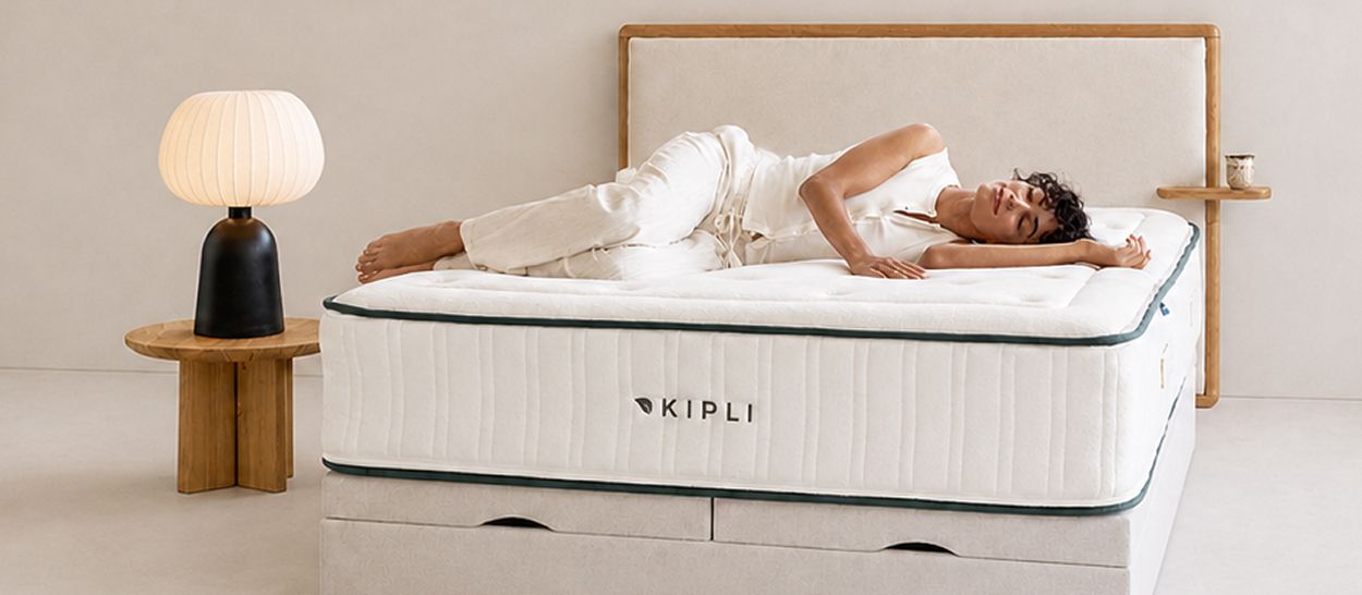 Femme allongée sereinement sur le côté sur un matelas en latex naturel Kipli dans une chambre épurée, illustrant le confort, la respirabilité et le caractère sain d'un couchage issu de la sève d'hévéa