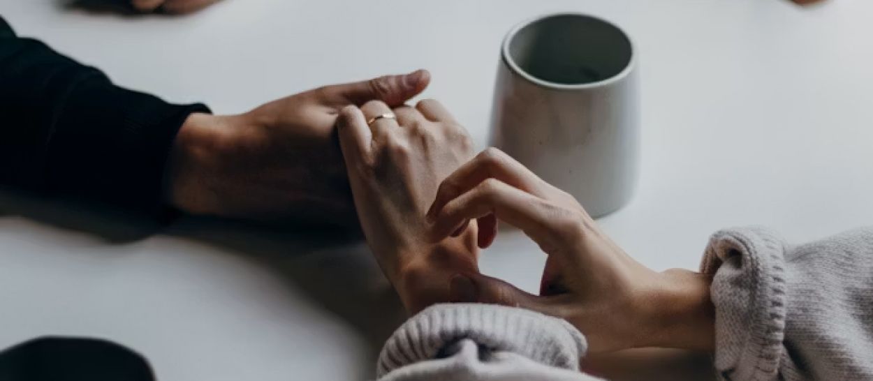 Deux personnes se tenant les mains autour d'une tasse lors d'un échange bienveillant, illustrant l'accompagnement psychologique du sommeil et l'idée que bien dormir repose d'abord sur le corps et le lâcher-prise