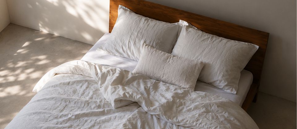 Lit avec linge de lit blanc en lin naturel froissé, draps légers et frais pour l'été